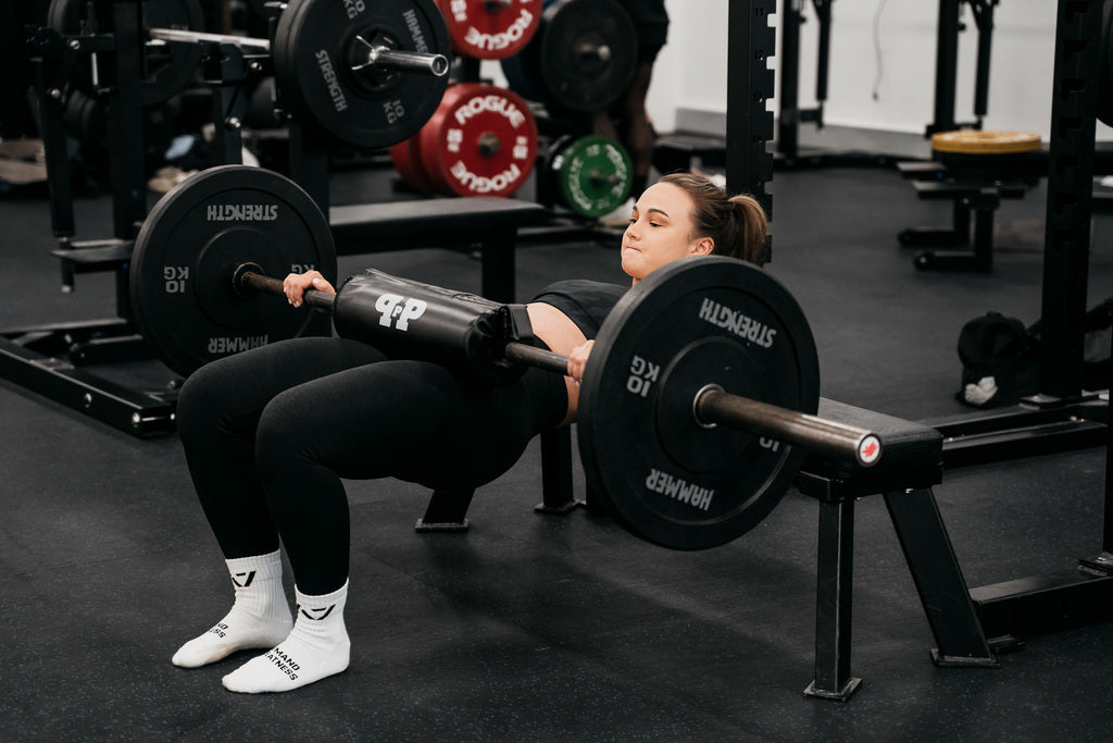 woman using barbell hip thrust pad in the gym