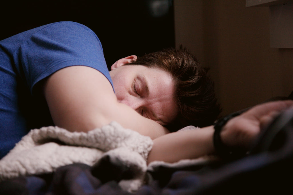 man wearing blue shirt sleeping in bed