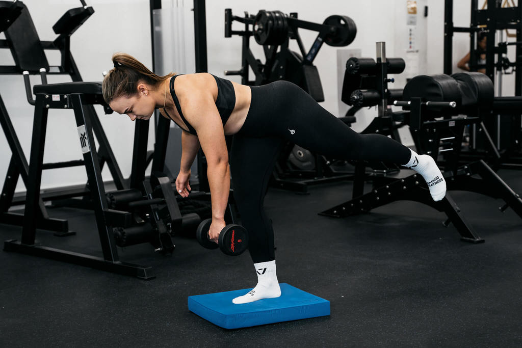 woman using nlue balance mat for stability exercises in gym