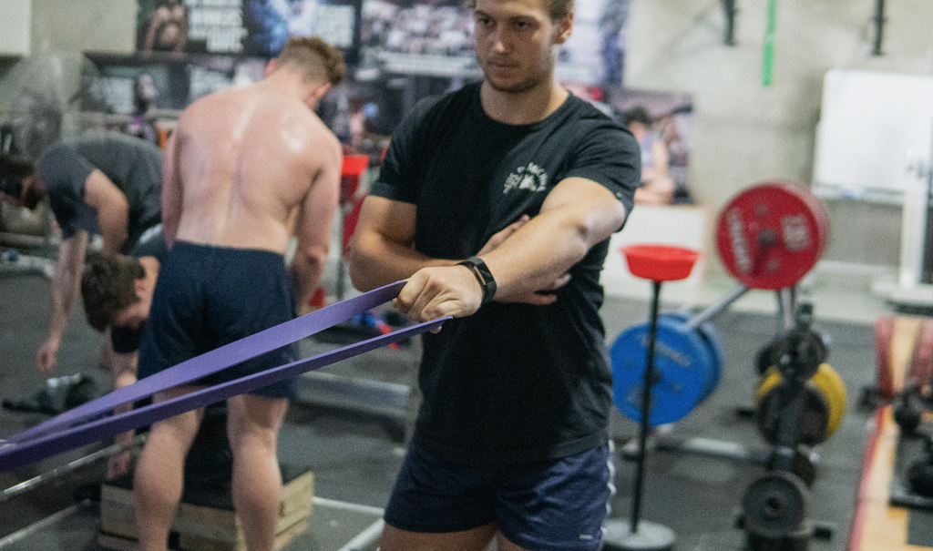 man using purple resistance band in gym