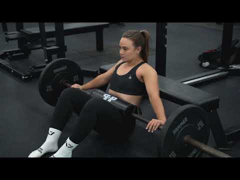 girl using barbell hip thrust pad while hip thrusting in gym